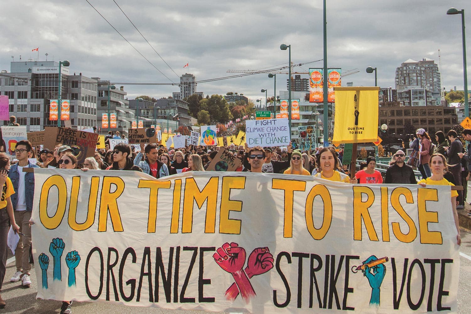 Activists lead a crowd across Vancouver’s Cambie Bridge with a banner that says “Our time to rise. Organize, Strike, Vote.”