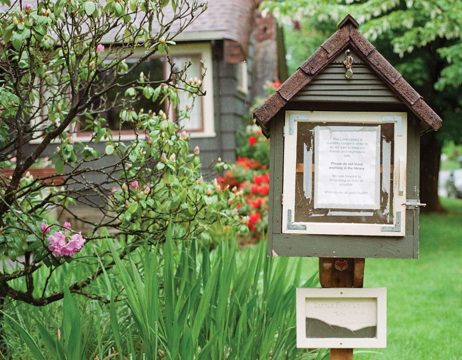 A little free library: a small, house-shaped box usually full of books. A sign on its door says it’s closed due to Covid-19.