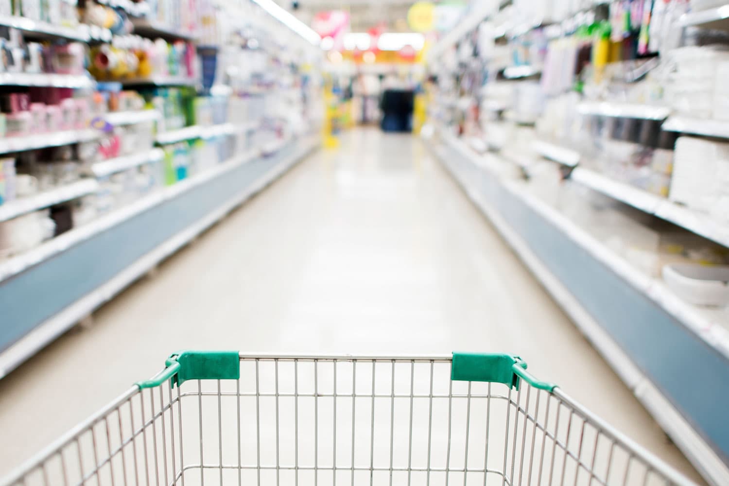 A shopping cart rolling down a brightly-lit grocery store aisle.