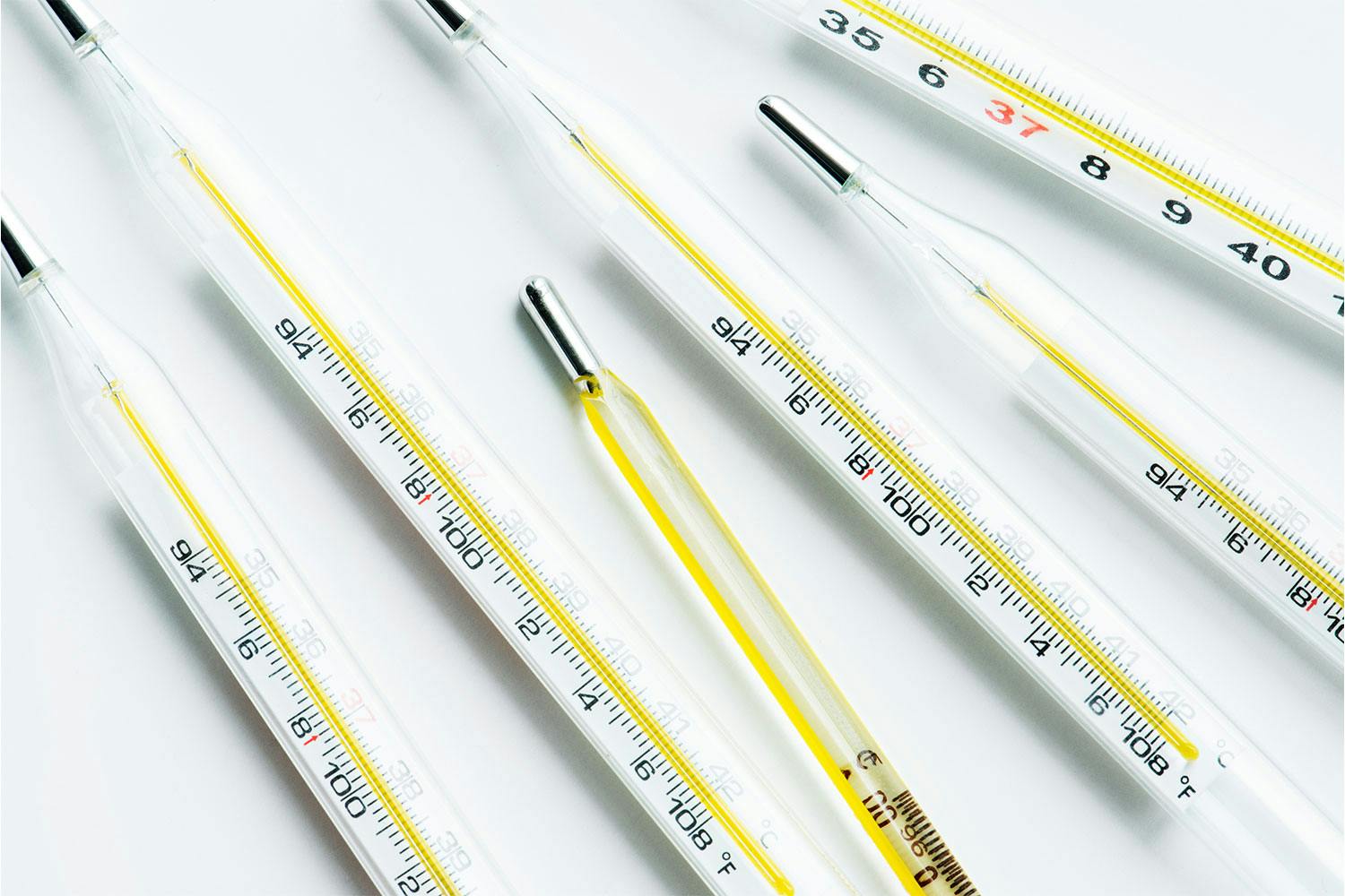 Six glass thermometers with yellow lines along their centres against a white background.