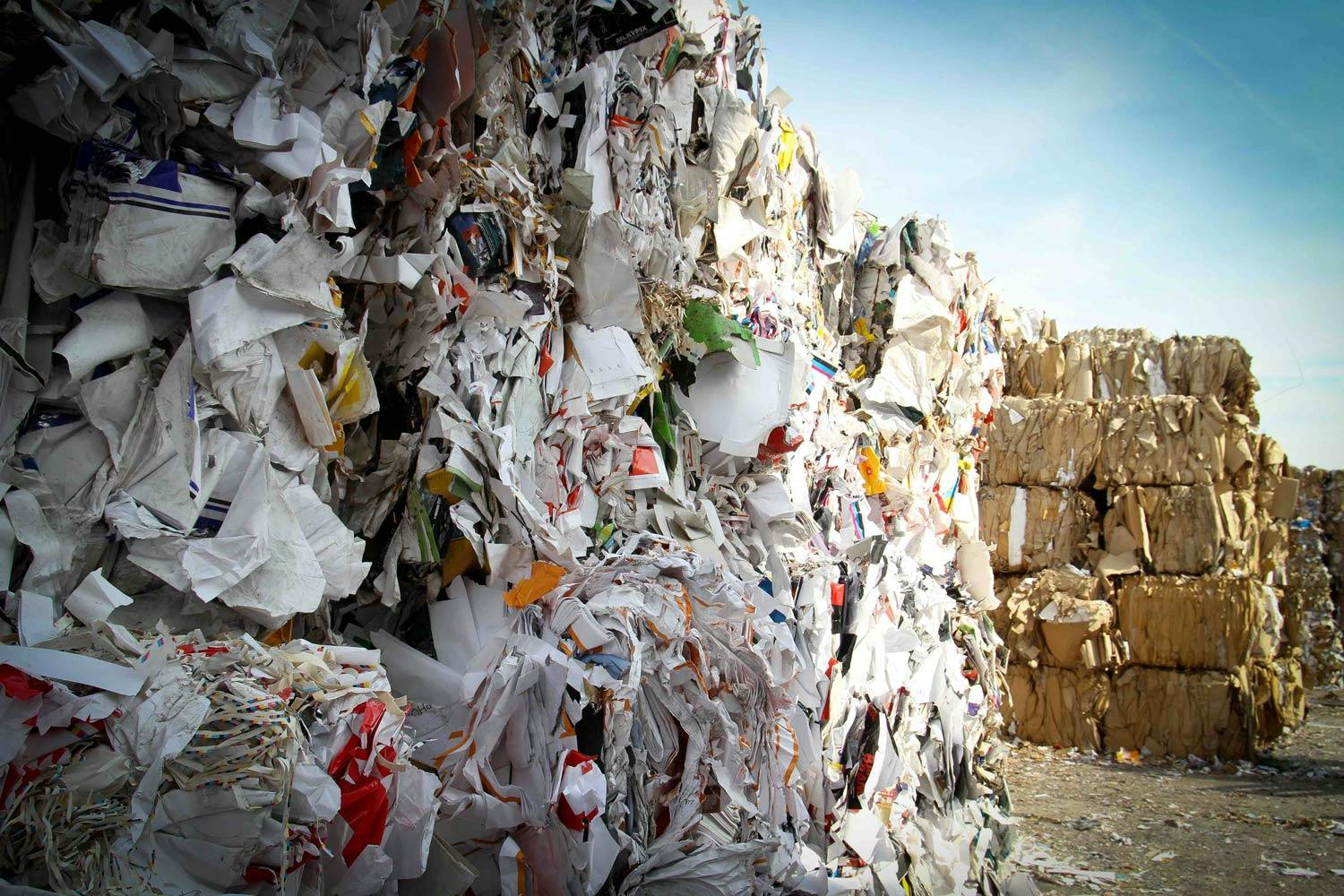 Stacks of recycling materials, including paper and cardboard, are bundled together in a recycling facility.